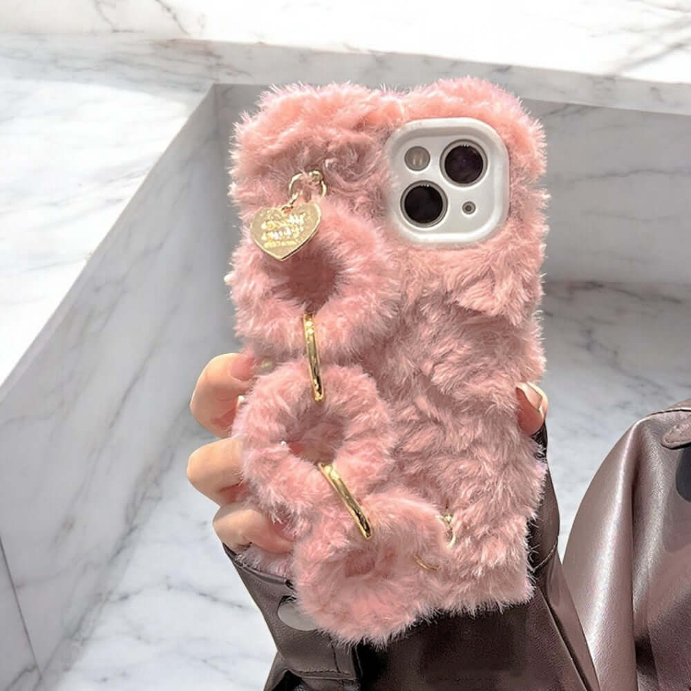 a person holding a pink fuzzy phone case