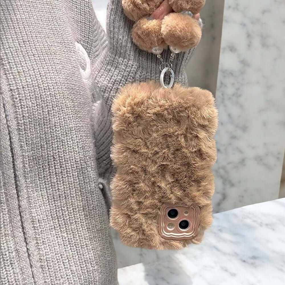 a teddy bear keychain hanging from a woman's hand