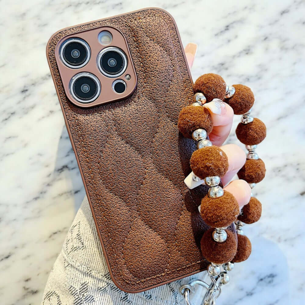 a person holding a cell phone case with a bunch of pom poms on