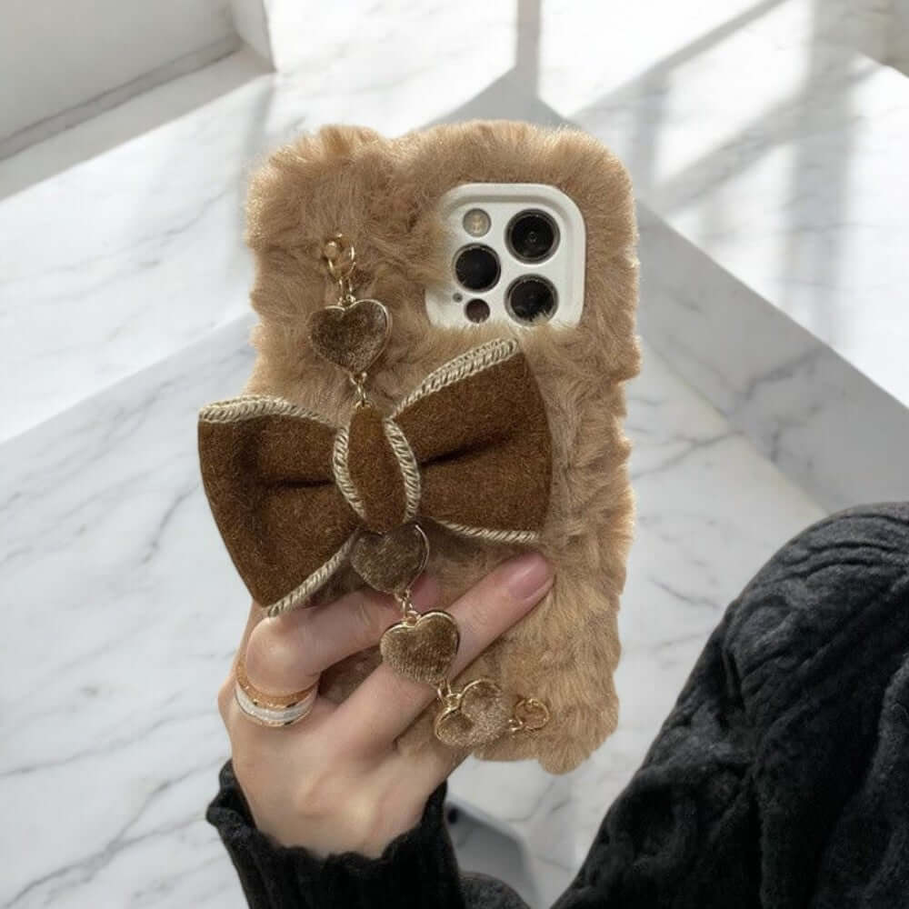 a person holding a cell phone case with a bow on it