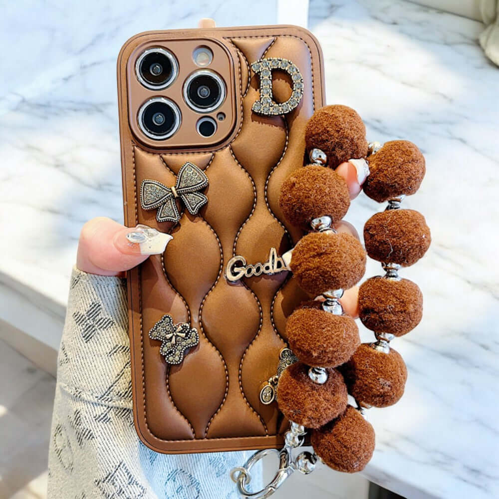 a person holding a cell phone case with a bunch of pom poms attached