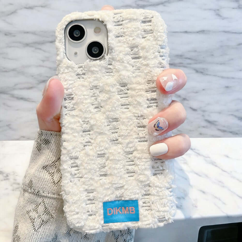 a woman holding up a phone case with white designs on it