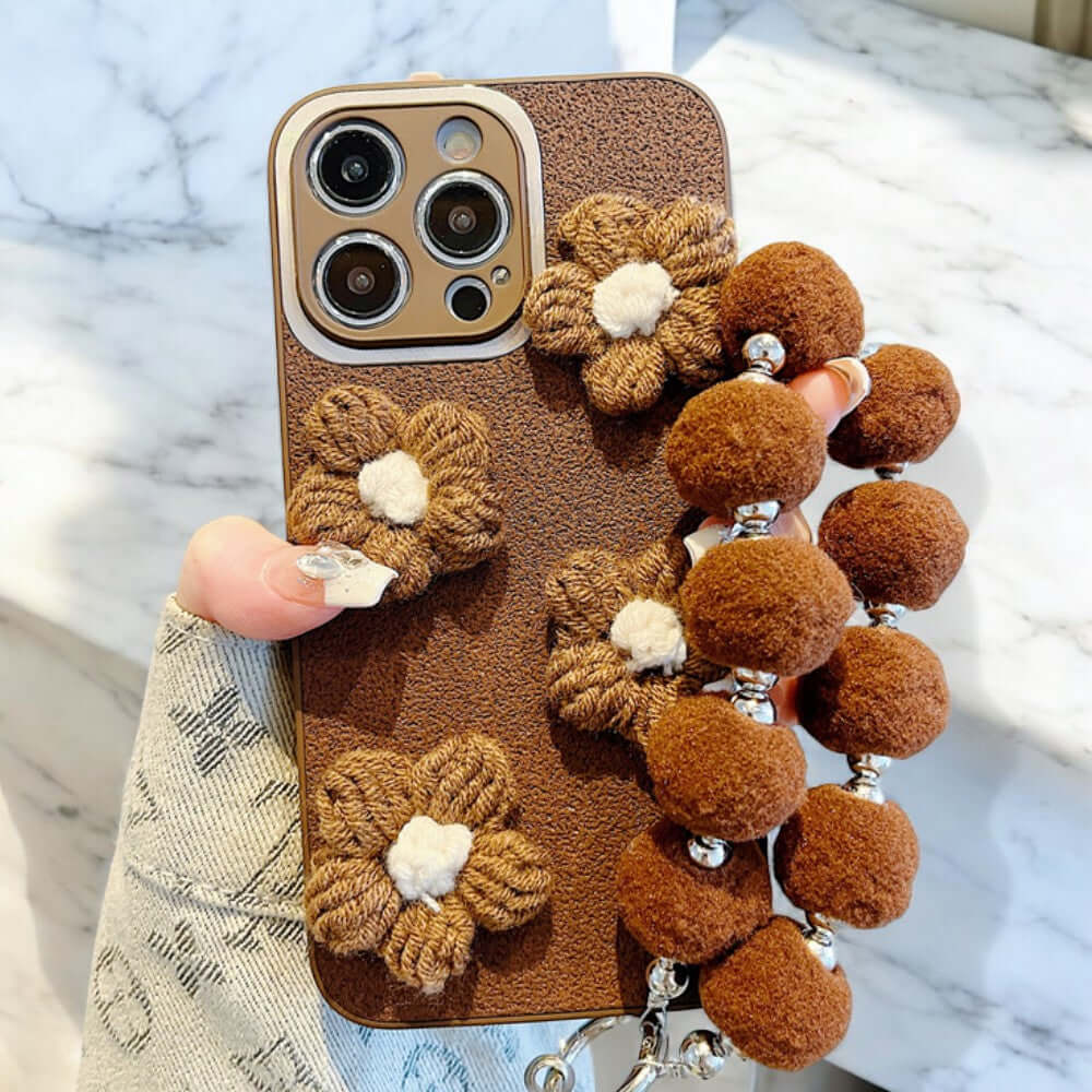 a person holding a cell phone case with a bunch of pom poms attached