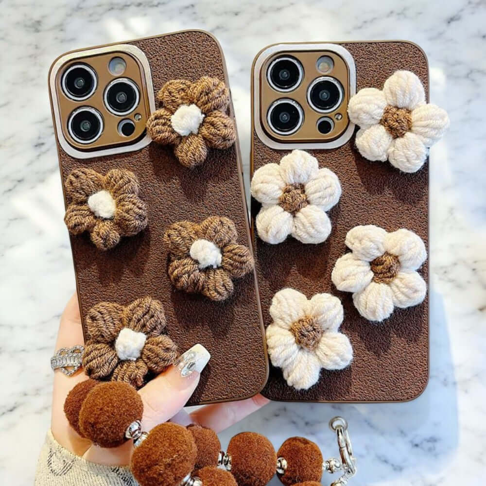 a person holding two cell phones with crocheted flowers on them