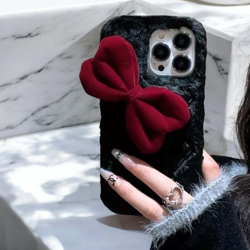 a woman holding a phone case with a red bow on it