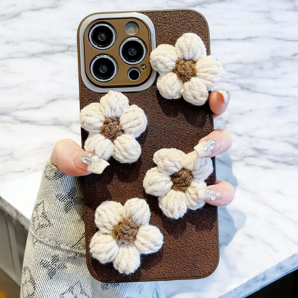 a person holding a cell phone with crocheted flowers on it